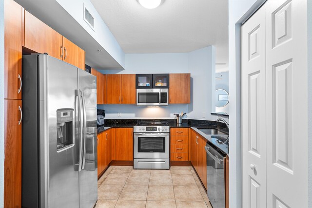 kitchen with sink, light tile patterned floors, stainless steel appliances, and a textured ceiling