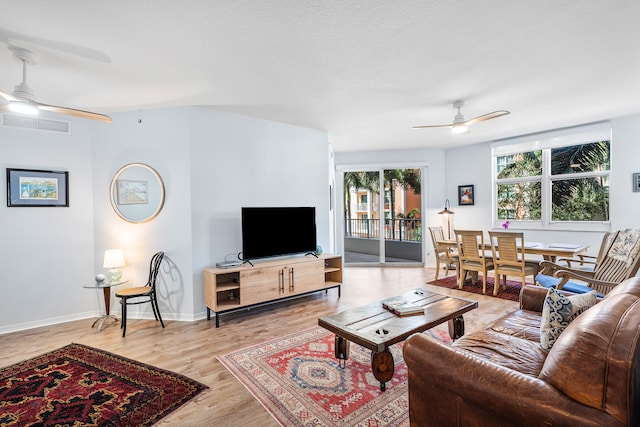 living room featuring wood-type flooring, a textured ceiling, and ceiling fan