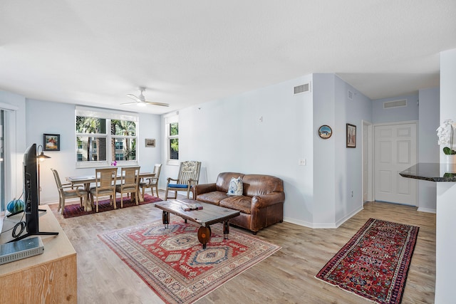 living room with ceiling fan, wood-type flooring, and a textured ceiling