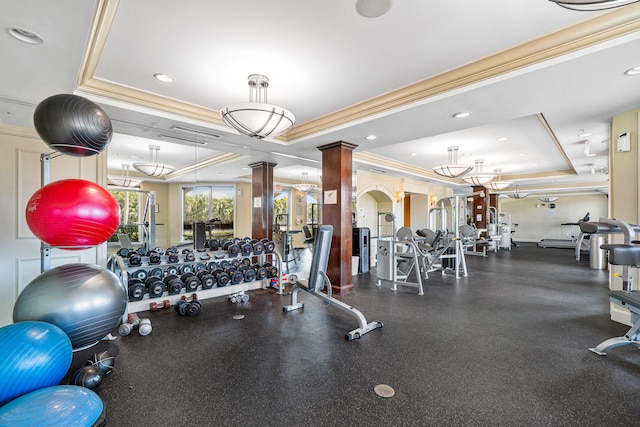 gym with a tray ceiling, decorative columns, and crown molding