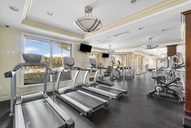 exercise room featuring a raised ceiling and ornamental molding