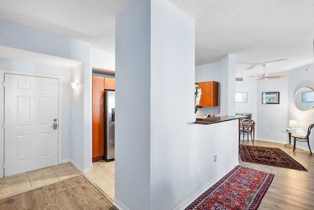 interior space featuring ceiling fan, a textured ceiling, and light hardwood / wood-style flooring