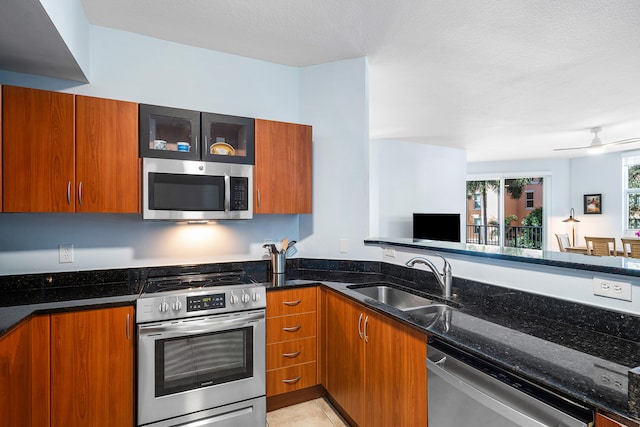 kitchen with dark stone counters, sink, ceiling fan, a textured ceiling, and appliances with stainless steel finishes