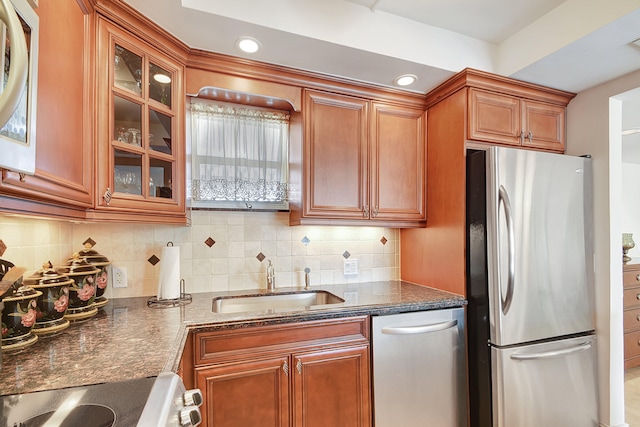 kitchen featuring backsplash, sink, stainless steel appliances, and dark stone counters