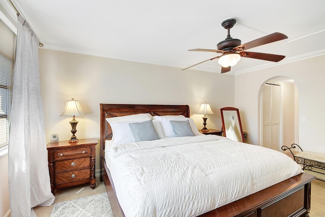 bedroom featuring ceiling fan, light tile patterned floors, crown molding, and a closet