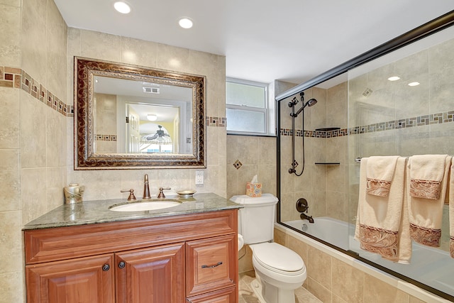 full bathroom featuring vanity, tile walls, and bath / shower combo with glass door