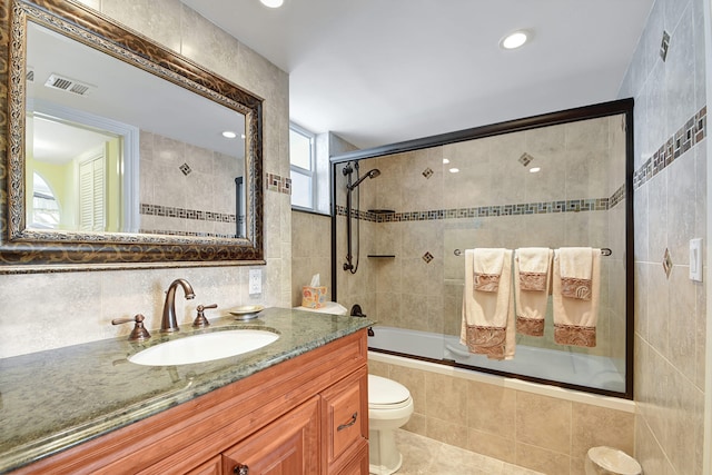 full bathroom with vanity, tile patterned floors, combined bath / shower with glass door, toilet, and tile walls