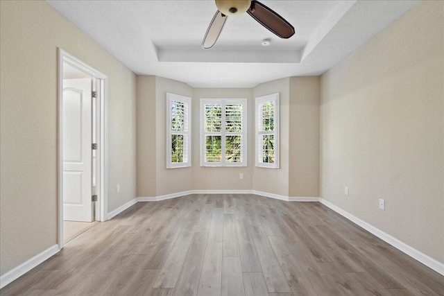 unfurnished room with a textured ceiling, light wood-type flooring, and ceiling fan