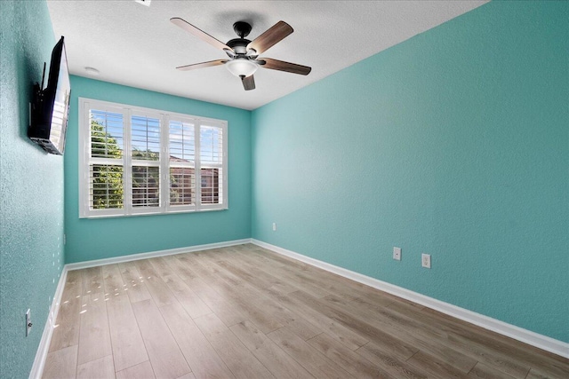 spare room with a textured ceiling, light hardwood / wood-style flooring, and ceiling fan