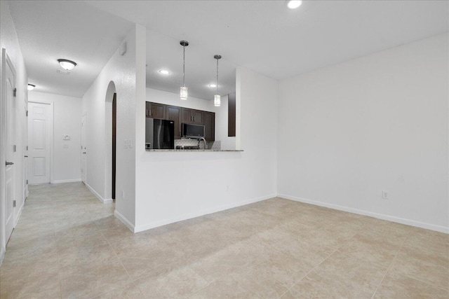 kitchen featuring black refrigerator, dark brown cabinetry, kitchen peninsula, and light tile patterned floors