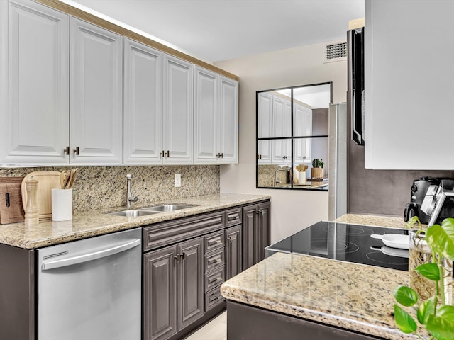 kitchen with sink, dishwasher, light stone countertops, white cabinets, and decorative backsplash