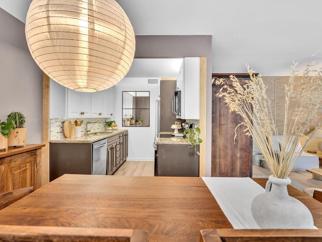 kitchen featuring light stone counters, backsplash, white cabinets, and stainless steel appliances