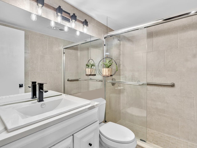 bathroom featuring toilet, tile walls, a stall shower, and vanity