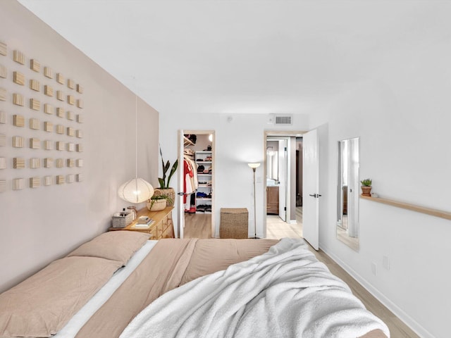 bedroom with a spacious closet, a closet, and light wood-type flooring