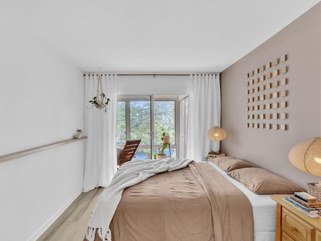 bedroom with baseboards, light wood-style floors, and access to outside