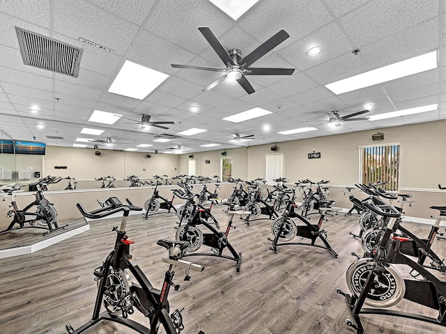 exercise room featuring visible vents, a drop ceiling, baseboards, and wood finished floors