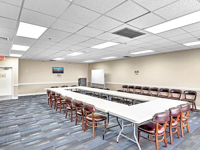 carpeted dining area with a paneled ceiling