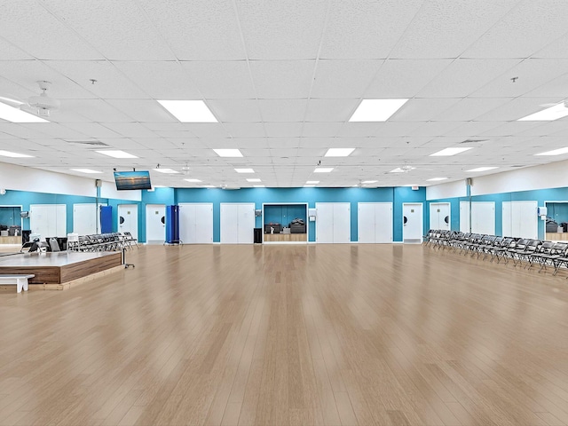 workout area with a paneled ceiling and wood finished floors