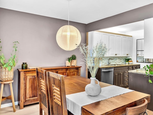 dining room with light wood-type flooring, bar area, and baseboards