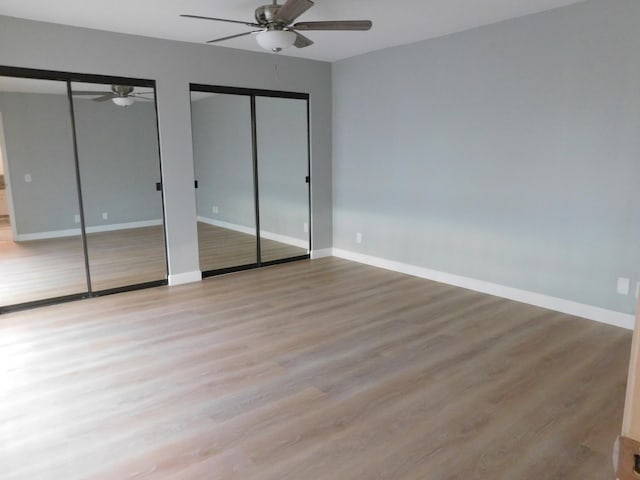 unfurnished bedroom with ceiling fan, light hardwood / wood-style floors, and two closets