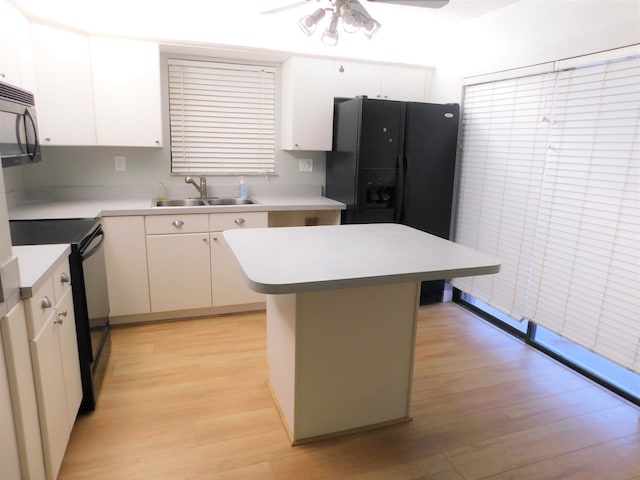 kitchen with sink, white cabinets, black appliances, and a kitchen island