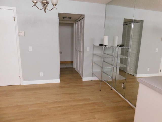 spare room featuring light hardwood / wood-style flooring and an inviting chandelier