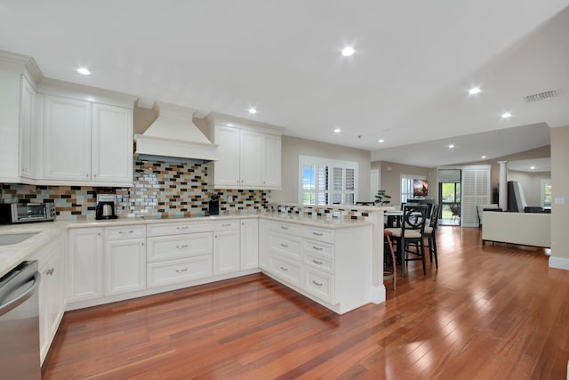 kitchen featuring custom exhaust hood, white cabinets, stainless steel dishwasher, decorative backsplash, and dark hardwood / wood-style flooring