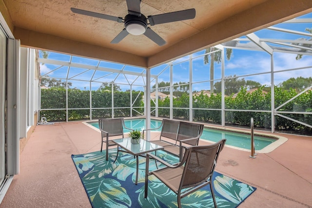 view of swimming pool featuring glass enclosure, ceiling fan, and a patio