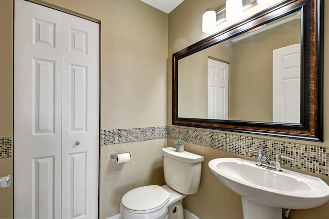 bathroom featuring tasteful backsplash, toilet, and sink