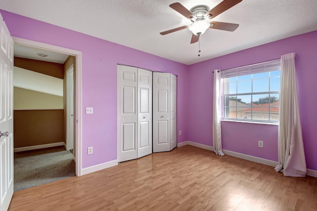 unfurnished bedroom with ceiling fan, a closet, a textured ceiling, and light wood-type flooring