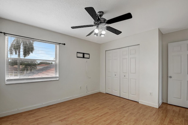 unfurnished bedroom with a closet, ceiling fan, light hardwood / wood-style flooring, and a textured ceiling