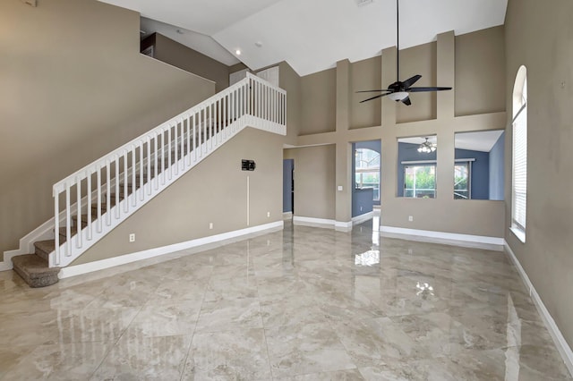 unfurnished living room with ceiling fan and a high ceiling