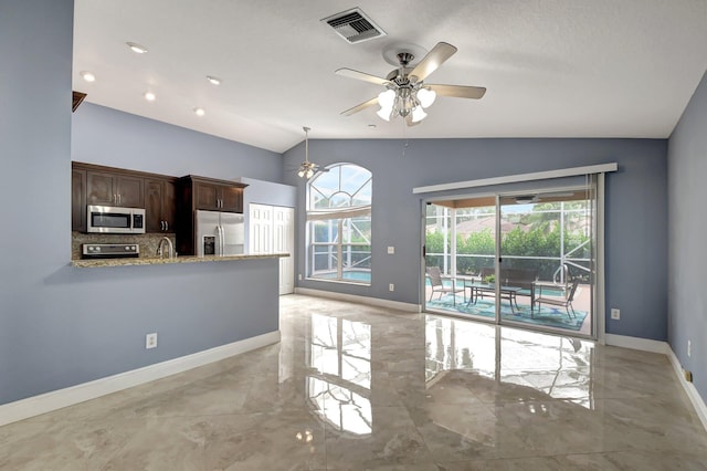 kitchen featuring lofted ceiling, kitchen peninsula, decorative backsplash, dark brown cabinetry, and stainless steel appliances