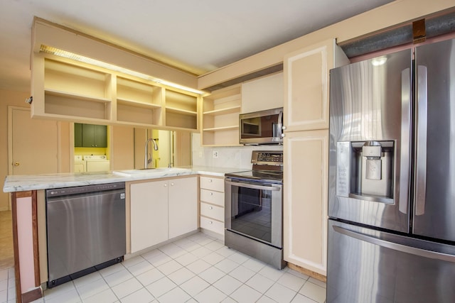 3537 SW Sunset Trace Cir, Palm City, FL 34990 - kitchen featuring appliances with stainless steel finishes, washer and clothes dryer, open shelves, a sink, and light tile patterned floors