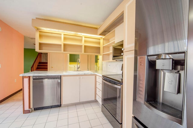 kitchen with white cabinetry, sink, stainless steel appliances, kitchen peninsula, and light tile patterned floors