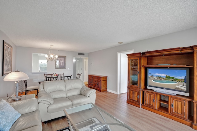 living room featuring light hardwood / wood-style flooring, a chandelier, and a textured ceiling