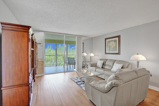 living room featuring a wall of windows, a textured ceiling, and light wood-type flooring