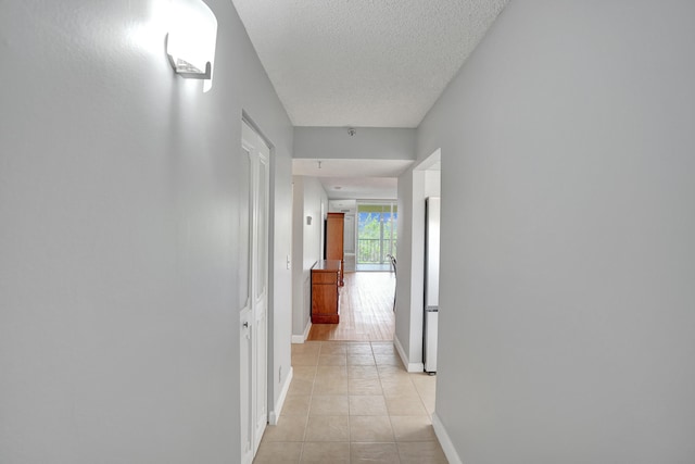 hallway with light tile patterned floors and a textured ceiling