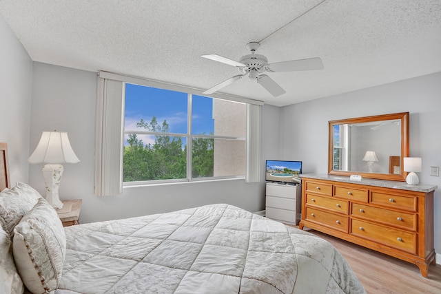 bedroom featuring multiple windows, ceiling fan, a textured ceiling, and light wood-type flooring