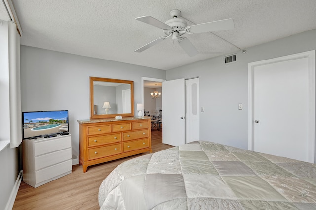 bedroom featuring a textured ceiling, ceiling fan with notable chandelier, light hardwood / wood-style flooring, and a closet