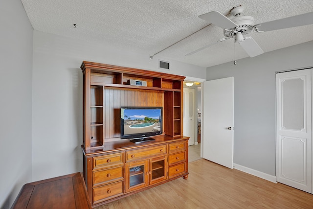 living room featuring a textured ceiling, light hardwood / wood-style flooring, and ceiling fan