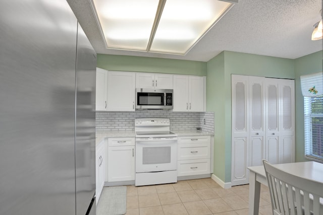 kitchen featuring white cabinets, light tile patterned floors, stainless steel appliances, and tasteful backsplash