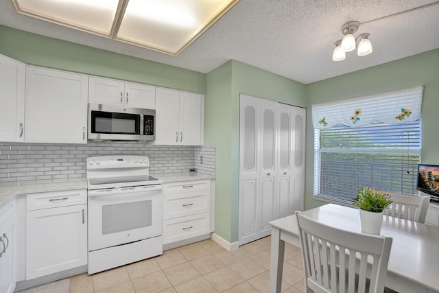 kitchen featuring white range with electric stovetop, tasteful backsplash, white cabinets, and light tile patterned flooring