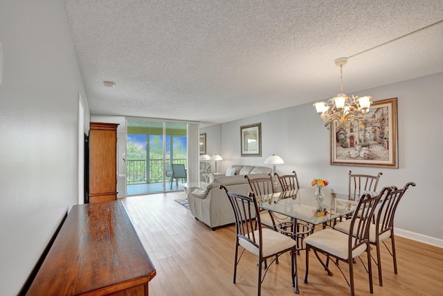 dining room featuring expansive windows, light hardwood / wood-style floors, a textured ceiling, and a notable chandelier