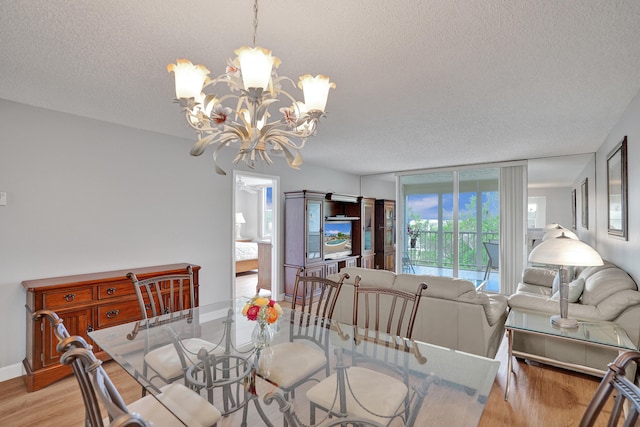 dining area with a chandelier, a textured ceiling, and light hardwood / wood-style flooring