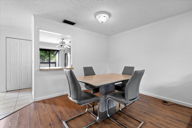 dining space featuring ceiling fan, dark wood-type flooring, a textured ceiling, and ornamental molding