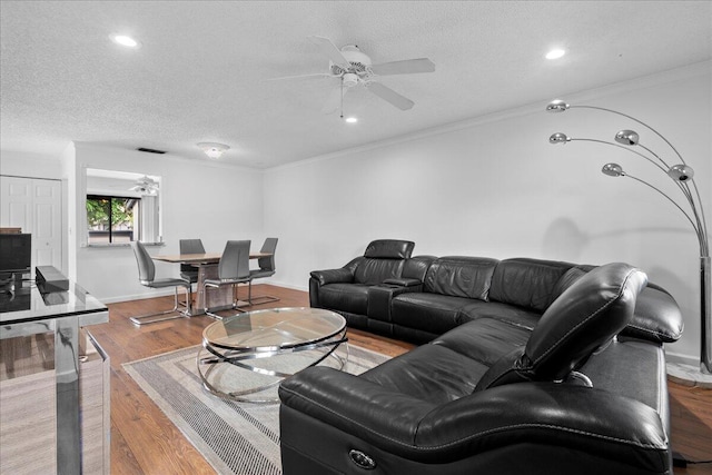 living room with hardwood / wood-style floors, a textured ceiling, ceiling fan, and crown molding