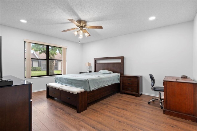 bedroom with ceiling fan, dark hardwood / wood-style flooring, and a textured ceiling