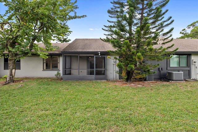 back of property with a sunroom, a yard, and central AC