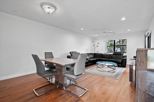 dining room featuring ceiling fan, light hardwood / wood-style floors, a textured ceiling, and ornamental molding